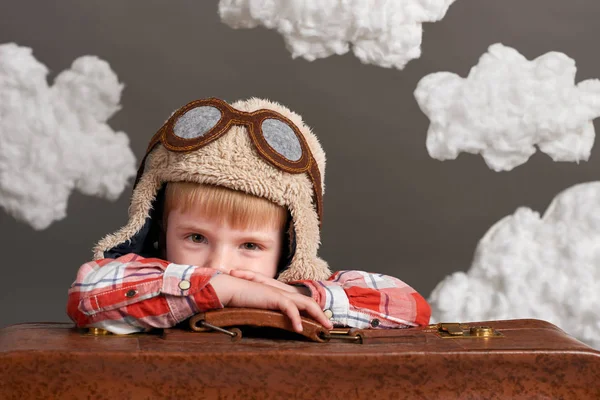 Αγόρι ντυμένος σαν ένα αεροπλάνο πιλοτικά κάθονται μεταξύ τα σύννεφα με παλιά βαλίτσα και όνειρα — Φωτογραφία Αρχείου