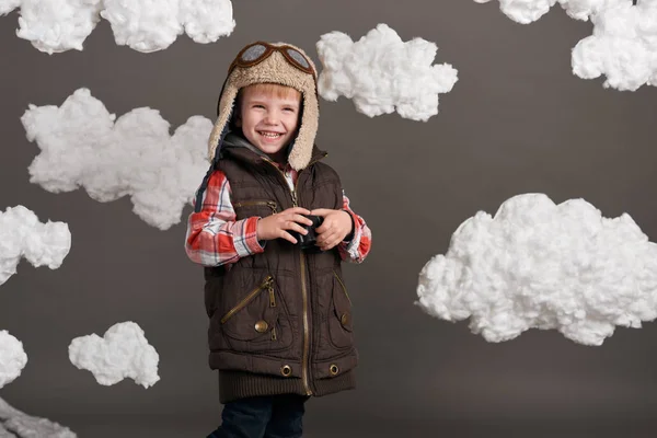 Αγόρι ντυμένος σαν πιλότος αεροπλάνου στέκεται ανάμεσα στα σύννεφα και μοιάζει με κιάλια — Φωτογραφία Αρχείου