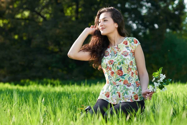 Hermosa chica sentada en un claro en el parque, sol brillante y sh — Foto de Stock