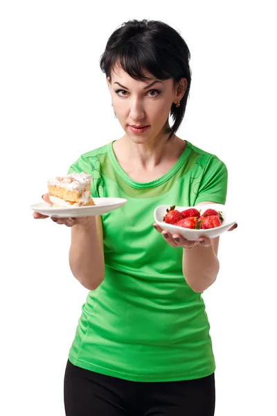 Girl choice between strawberry and sweet cake, isolate on white background, healthy food concept — Stock Photo, Image