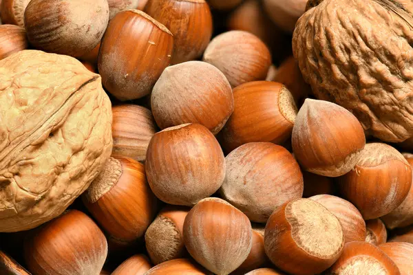 Macro photo of nuts and walnuts - autumn harvest and healthy food concept. Yellow leaves. Still life on wooden background. — Stock Photo, Image