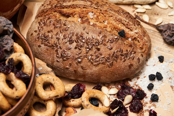 Taze ekmek, simit, kurutulmuş meyve, tohumlar, tuz, kavanoz ve buğday - hala hayat ve sağlıklı beslenme kavramı — Stok fotoğraf