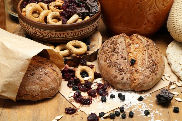 fresh bread, bagels, dried fruits, seeds, salt, jar and wheat on the wooden - still life and healthy eating concept