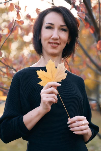 Schöne elegante Frau, die im Herbst im Stadtpark steht und posiert — Stockfoto