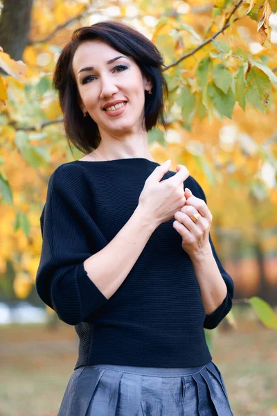 Bella donna elegante in piedi e in posa in un parco cittadino in autunno — Foto Stock