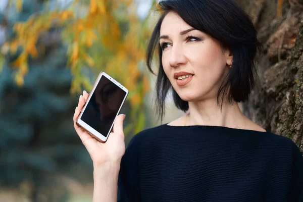 Vacker elegant kvinna talar via telefon och poserar i en stadspark på hösten — Stockfoto