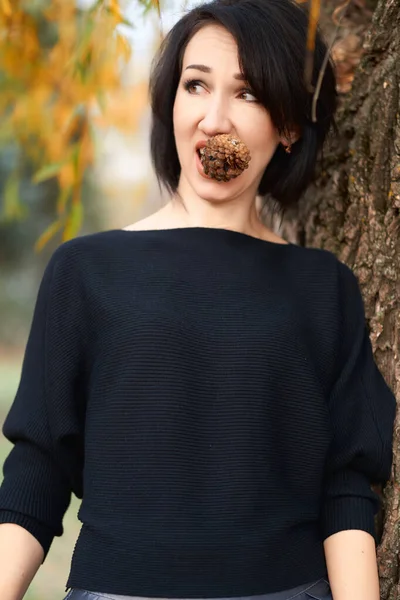 Mulher elegante bonita se divertindo e comendo cone de abeto em um parque da cidade no outono — Fotografia de Stock