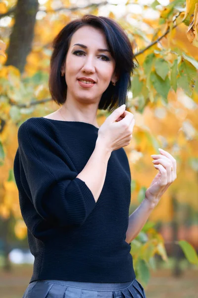 Schöne elegante Frau, die im Herbst im Stadtpark steht und posiert — Stockfoto