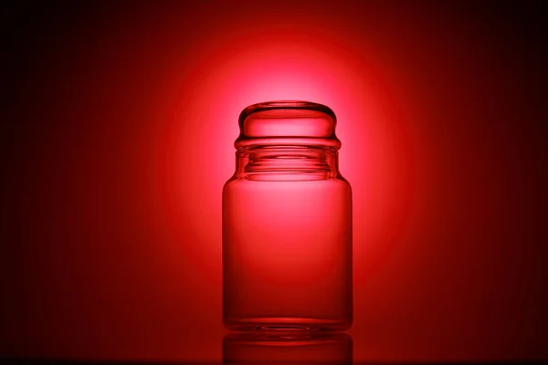 Empty glass jar on a red and black background — Stock Photo, Image