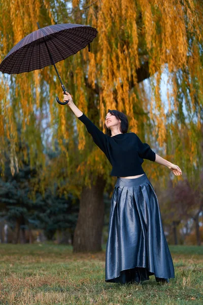 Piękna elegancka kobieta otwiera parasol w jesiennym parku miejskim — Zdjęcie stockowe