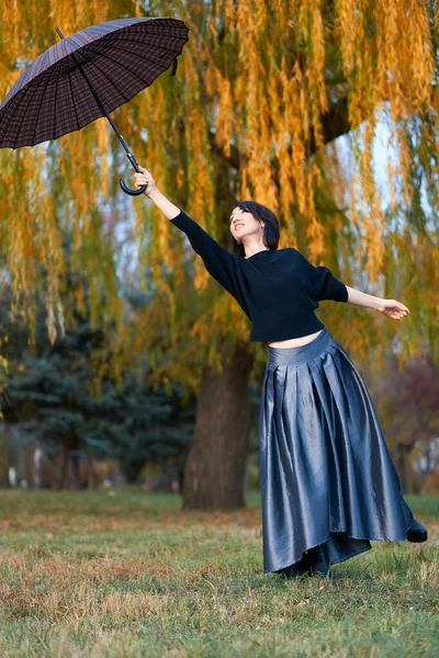 Piękna elegancka kobieta otwiera parasol w jesiennym parku miejskim — Zdjęcie stockowe