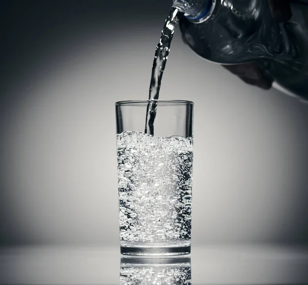 Pouring sparkling water in a glass on a dark background — Stock Photo, Image