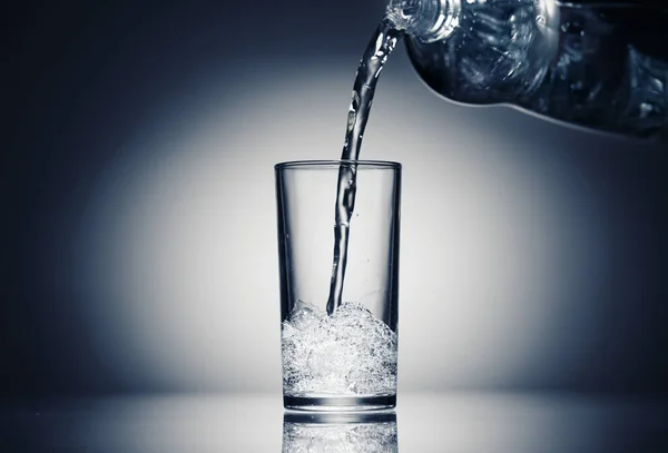 Verter agua con gas en un vaso sobre un fondo azul oscuro —  Fotos de Stock