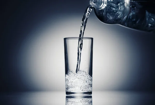 Pouring sparkling water in a glass on a dark blue background — Stock Photo, Image