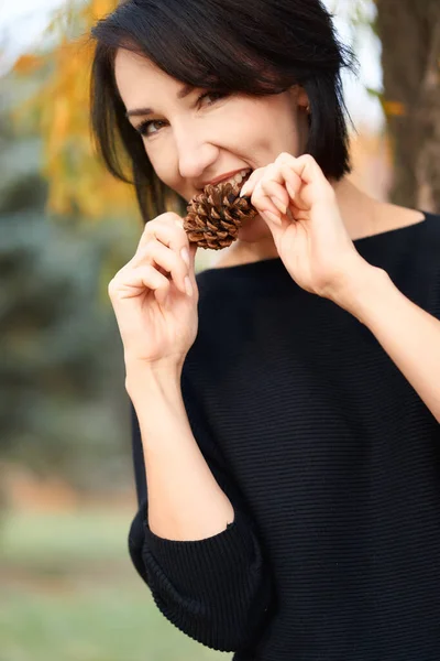 Mulher elegante bonita se divertindo e comendo cone de abeto em um parque da cidade no outono — Fotografia de Stock