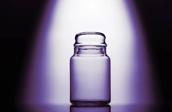 Empty glass jar on a purple, black and white background with light effect — Stock Photo, Image