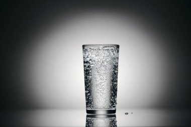 Karanlık bir arka planda bir bardak köpüklü su