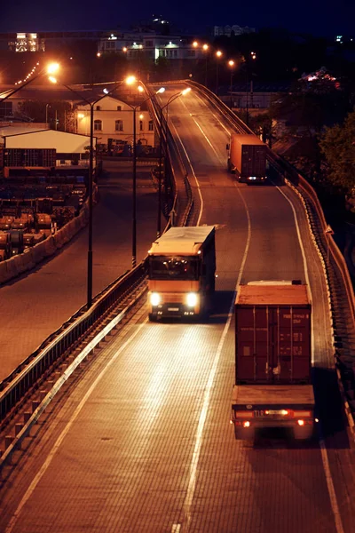 Truck with container rides on the road, freight cars in industrial seaport at night — Stock Photo, Image