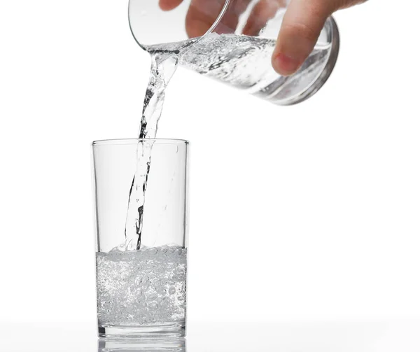 Gießen von sprudelndem Wasser in einem Glas auf weißem Hintergrund, isoliertes Objekt — Stockfoto