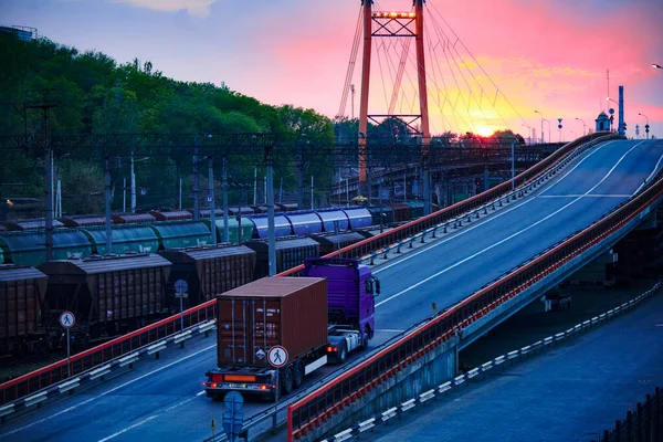 Vrachtwagen met containerritten op de weg, spoorvervoer, goederenauto 's in industriële zeehaven bij zonsondergang — Stockfoto