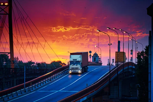 Köprüde konteynır taşıyan kamyon, güzel günbatımı, endüstriyel limanda yük vagonları, yol yukarı çıkıyor. — Stok fotoğraf