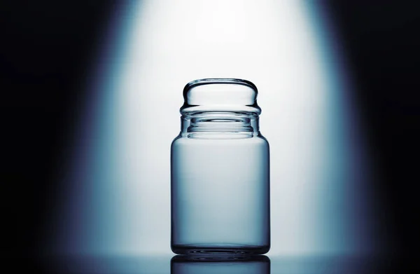 Empty glass jar on a blue and white background with light effect — Stock Photo, Image