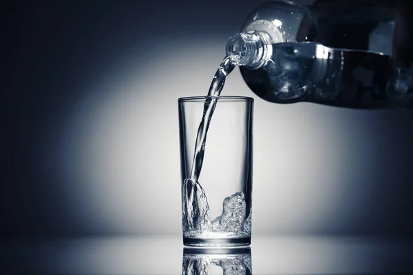 Gießen von sprudelndem Wasser in einem Glas auf dunkelblauem Hintergrund — Stockfoto