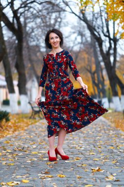 Güzel, zarif bir kadın, sonbahar mevsiminde, şehir caddesinde poz veriyor.