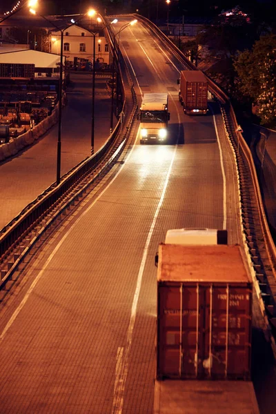 Truck with container rides on the road, freight cars in industrial seaport at night — Stock Photo, Image