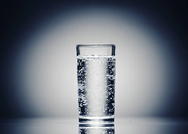 Satu gelas air mineral pada latar belakang biru tua — Stok Foto