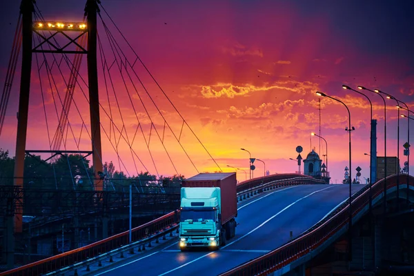 Köprüde konteynır taşıyan kamyon, güzel günbatımı, endüstriyel limanda yük vagonları, yol yukarı çıkıyor. — Stok fotoğraf