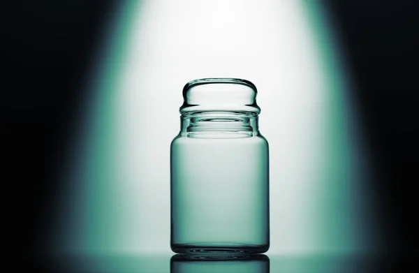 Empty glass jar on a green, black and white background with light effect — Stock Photo, Image