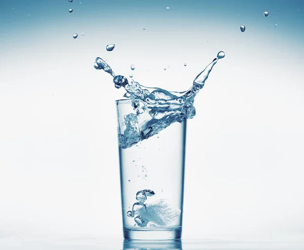 Ein Glas Wasser mit Spritzwasser aus fallenden Eiswürfeln, weißer Hintergrund, isoliertes Objekt — Stockfoto
