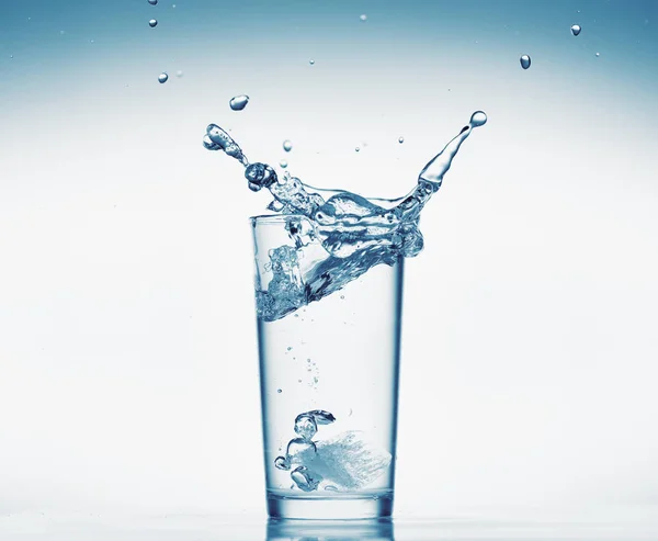 One glass of water with splash from falling ice cube, white background, isolated object — Stock Photo, Image