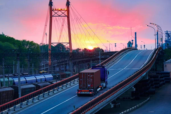 LKW mit Containerfahrten auf der Straße, Eisenbahnverkehr, Güterwagen im Industriehafen bei Sonnenuntergang — Stockfoto