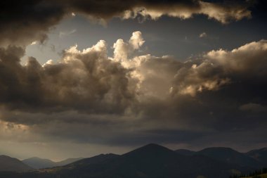 Karpatya dağlarında altın gün batımı - güzel yaz manzarası, tepelerde yaylalar, karanlık bulutlu gökyüzü ve parlak güneş ışığı, çayır ve kır çiçekleri