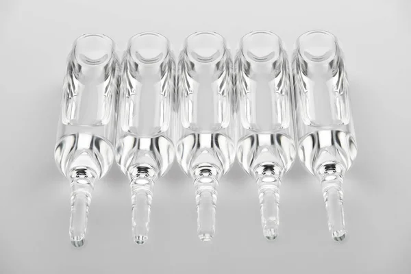 Ampoules. Transparent capsules with liquid on white background. Medicament for health care. Pharmaceutical industry. Pharmacy. — Stock Photo, Image