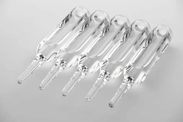 Ampoules. Transparent capsules with liquid on white background. Medicament for health care. Pharmaceutical industry. Pharmacy. — Stok fotoğraf