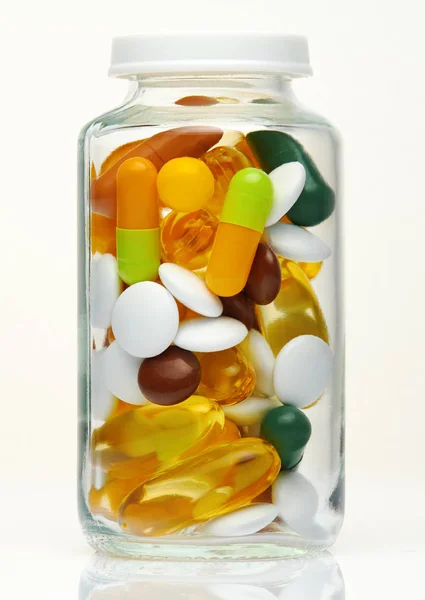 Glass bottle full of colorful pills, tablets, vitamins, drugs, omega 3 fish oil, gel capsules, medicament and food supplement for healthcare. Pharmaceutical industry. Pharmacy. Macro photo. — Stok fotoğraf