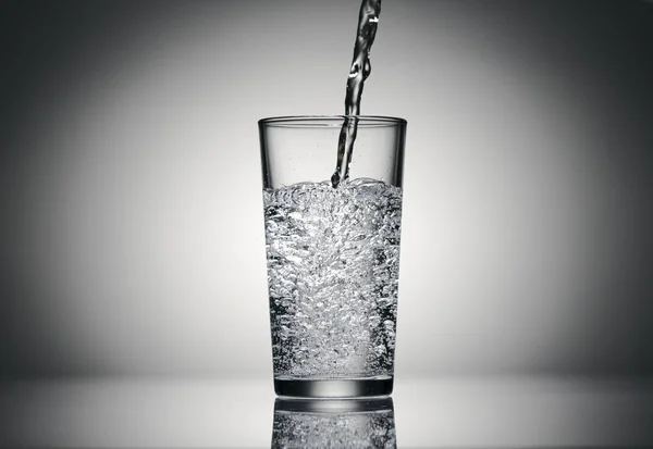 Verter agua con gas en un vaso sobre un fondo oscuro —  Fotos de Stock