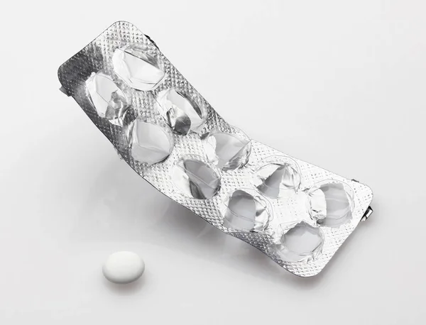 Prázdný, použitý, otevřený blistr s poslední bílou pilulkou na bílém pozadí - koncept zdravotní péče a léků. Farmaceutický průmysl. Lékárna. — Stock fotografie