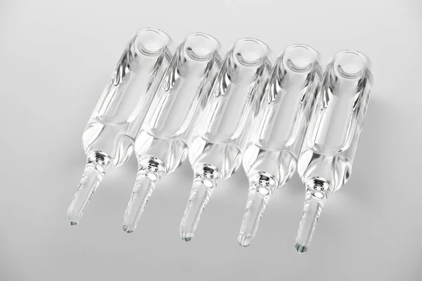 Ampoules. Transparent capsules with liquid on white background. Medicament for health care. Pharmaceutical industry. Pharmacy. — Stock Photo, Image