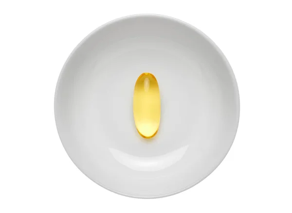 Omega 3 fish oil gel capsule in center of white round plate. Isolated on white background. — Stock Photo, Image