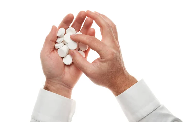 Mão de homem com um punhado de grandes pílulas brancas isoladas no fundo branco. Camisa branca, estilo de negócio. Medicamento e suplemento alimentar para cuidados de saúde. Indústria farmacêutica. Farmácia . — Fotografia de Stock