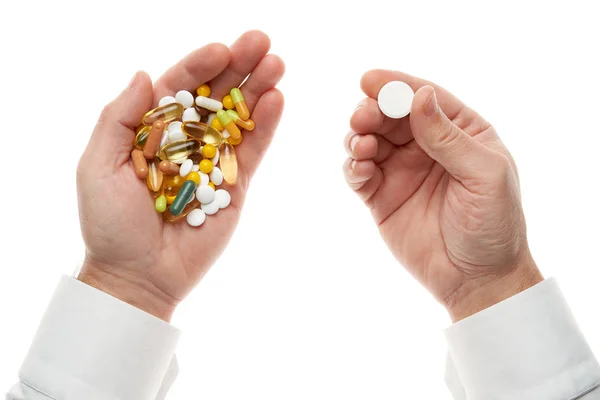 Man hand het krijgen van een pil van een handvol pillen, tabletten, vitaminen, drugs, capsules geïsoleerd op witte achtergrond. Wit shirt, zakelijke stijl. Gezondheidszorgconcept. Farmaceutische industrie. Apotheek. — Stockfoto