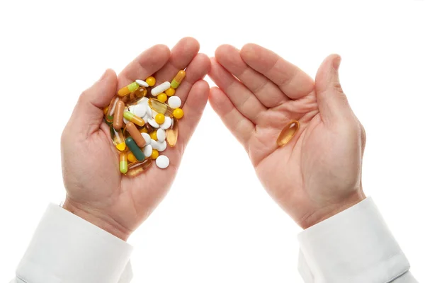 Man hand het krijgen van een pil van een handvol pillen, tabletten, vitaminen, drugs, capsules geïsoleerd op witte achtergrond. Wit shirt, zakelijke stijl. Gezondheidszorgconcept. Farmaceutische industrie. Apotheek. — Stockfoto