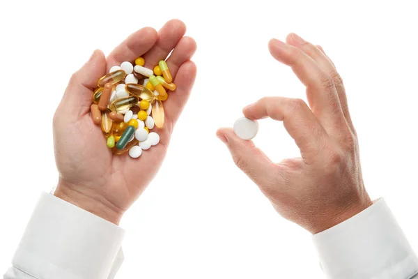Mann Hand bekommt eine Pille aus einer Handvoll Pillen, Tabletten, Vitaminen, Medikamenten, Kapseln isoliert auf weißem Hintergrund. Weißes Hemd, Business-Stil. Gesundheitskonzept. Pharmaindustrie. Apotheke. — Stockfoto