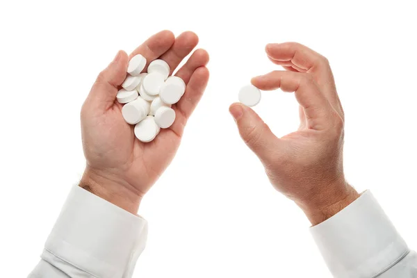 Mão de homem com um punhado de grandes pílulas brancas isoladas no fundo branco. Camisa branca, estilo de negócio. Medicamento e suplemento alimentar para cuidados de saúde. Indústria farmacêutica. Farmácia . — Fotografia de Stock