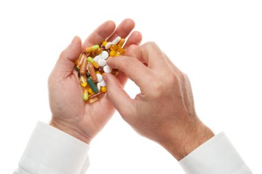 Man hand getting one pill from handful of pills, tablets, vitamins, drugs, capsules isolated on white background. White shirt, business style. Health care concept. Pharmaceutical industry. Pharmacy.