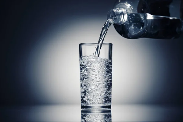 Заливая газированную воду в стакан на темно-синем фоне — стоковое фото